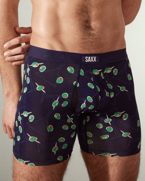 A man wearing a pair of navy blue boxer briefs printed with cocktail olives on sticks.